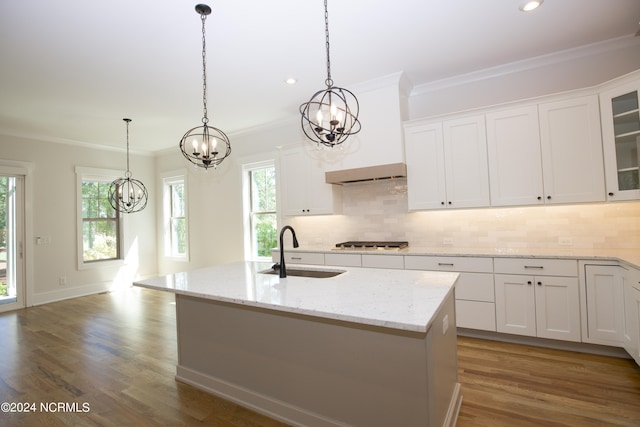 kitchen with pendant lighting, sink, white cabinetry, and a kitchen island with sink