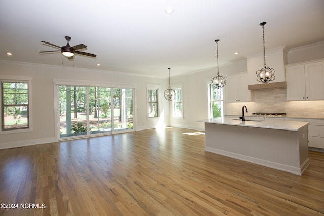 kitchen featuring a kitchen island with sink, crown molding, white cabinetry, ceiling fan, and light wood-type flooring