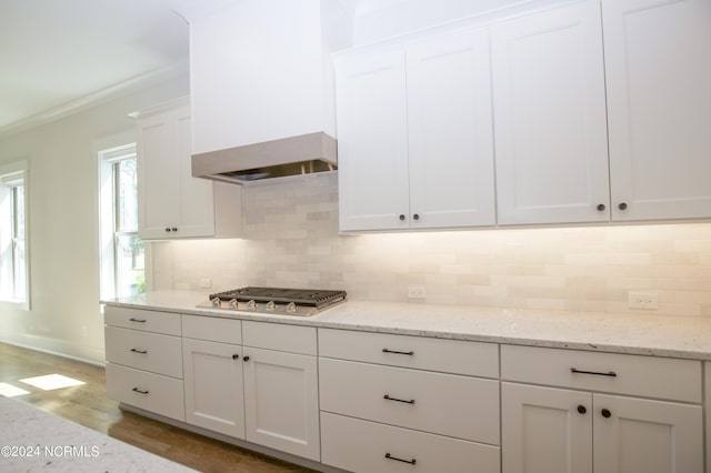 kitchen featuring light stone countertops, stainless steel gas stovetop, decorative backsplash, white cabinetry, and light wood-type flooring