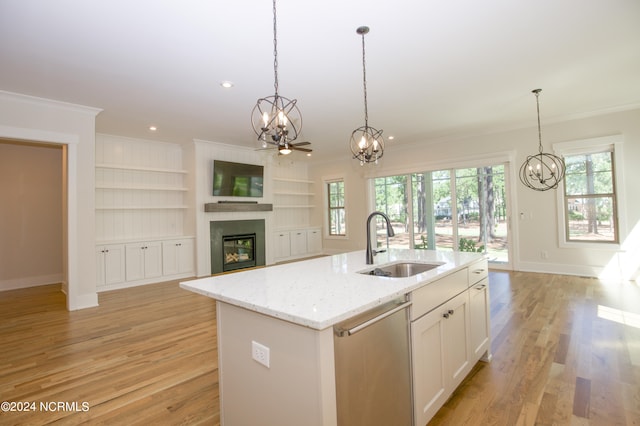 kitchen featuring light wood-type flooring, ceiling fan with notable chandelier, a center island with sink, sink, and stainless steel dishwasher