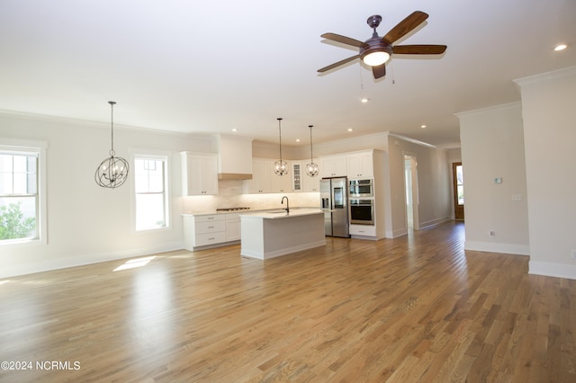 kitchen with white cabinets, ceiling fan with notable chandelier, a center island with sink, and light hardwood / wood-style flooring