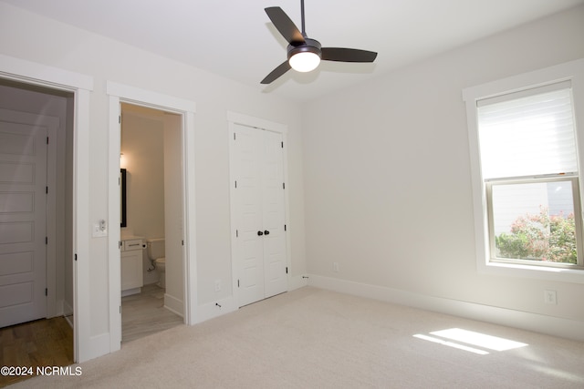 unfurnished bedroom with light colored carpet, connected bathroom, ceiling fan, and a closet