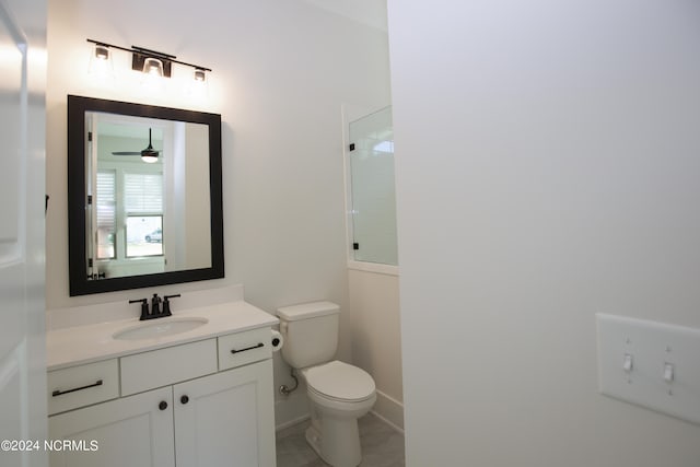 bathroom featuring vanity, toilet, walk in shower, and ceiling fan