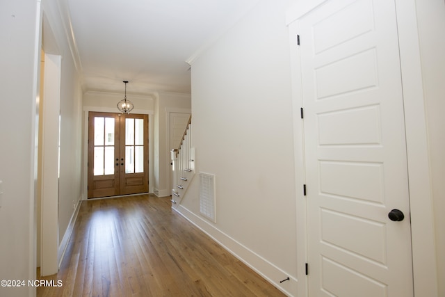 entryway featuring an inviting chandelier, light hardwood / wood-style floors, crown molding, and french doors