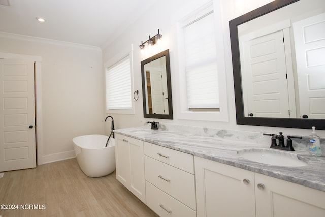 bathroom with plenty of natural light, a tub, vanity, and wood-type flooring