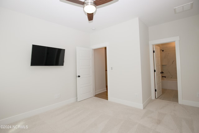 unfurnished bedroom featuring light colored carpet, connected bathroom, and ceiling fan