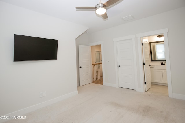 unfurnished bedroom with light colored carpet, ceiling fan, sink, and ensuite bath