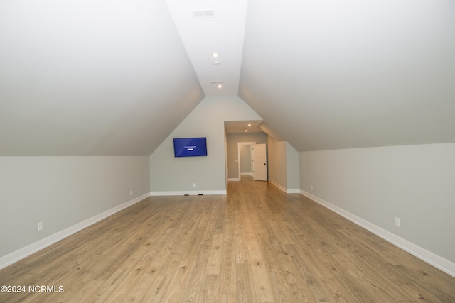 additional living space featuring light wood-type flooring and vaulted ceiling