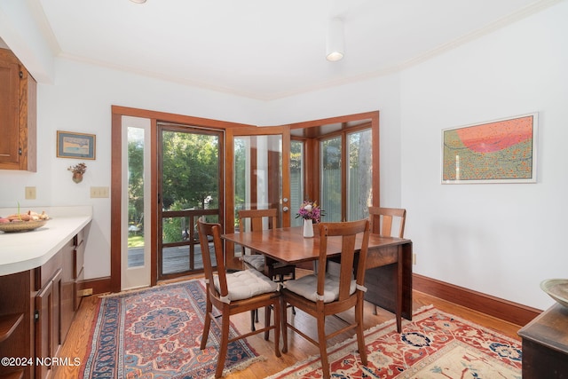 dining room with ornamental molding and light wood-type flooring