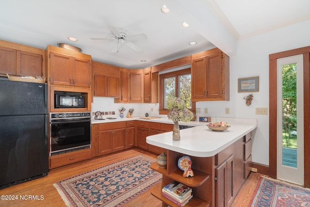 kitchen with kitchen peninsula, black appliances, crown molding, light wood-type flooring, and ceiling fan