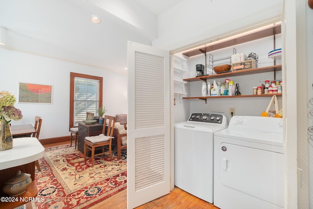 clothes washing area with light hardwood / wood-style flooring and separate washer and dryer