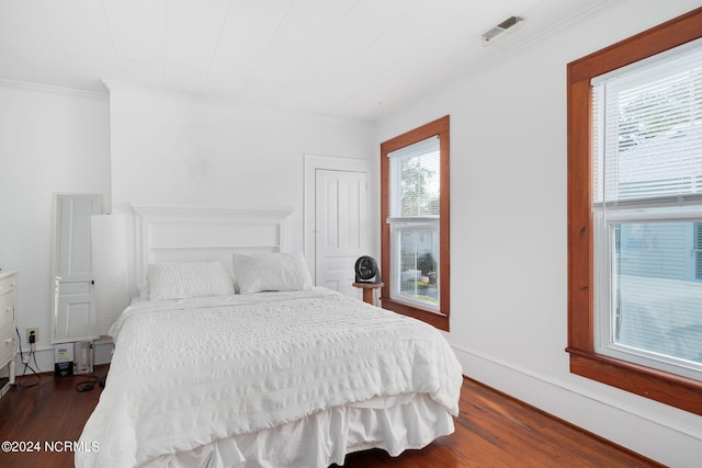 bedroom featuring ornamental molding, multiple windows, and dark hardwood / wood-style floors