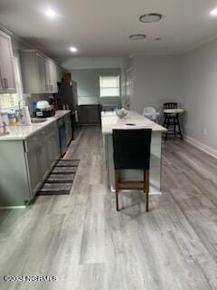 kitchen with light wood-type flooring, gray cabinetry, a center island, and a breakfast bar