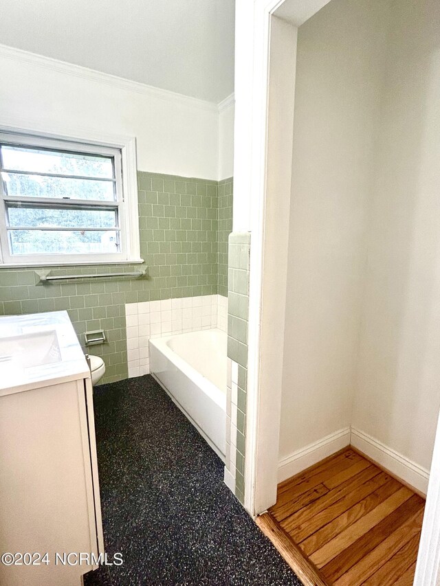 bathroom with hardwood / wood-style floors, toilet, tile walls, a bathtub, and vanity