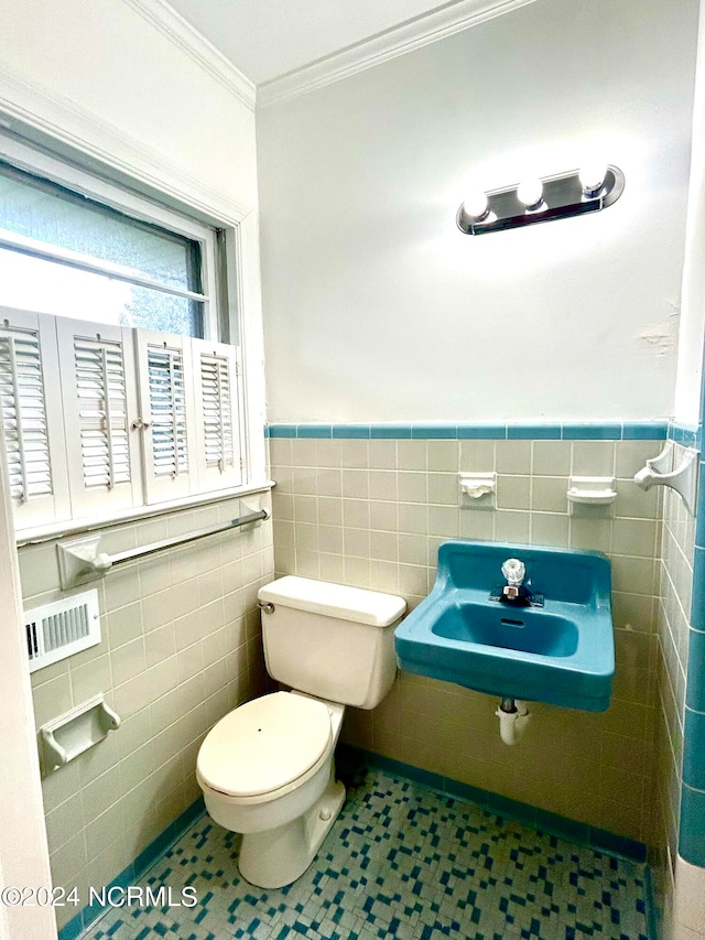 bathroom featuring tile walls, toilet, ornamental molding, and sink