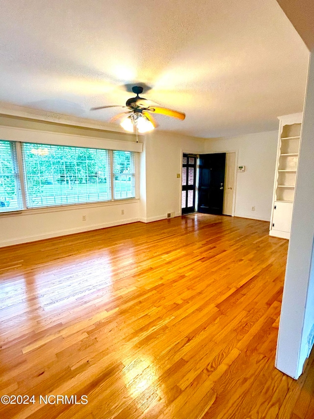 unfurnished living room with a textured ceiling, wood-type flooring, and ceiling fan