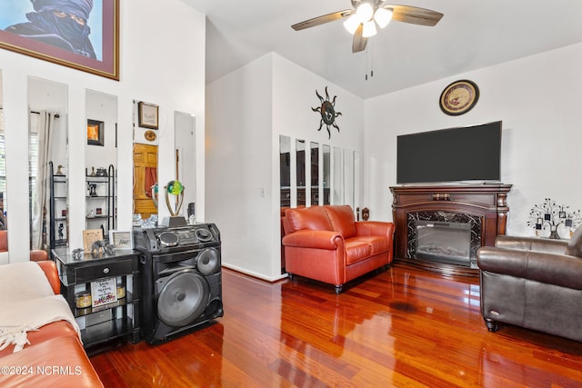 living room featuring a fireplace, dark wood-type flooring, a high ceiling, and ceiling fan