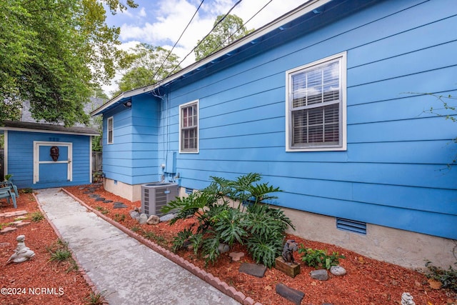 view of home's exterior with central air condition unit and a storage unit