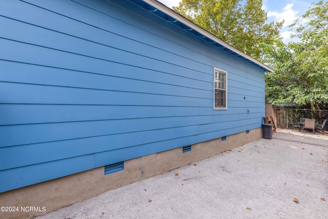 view of side of property with crawl space, a patio area, and fence