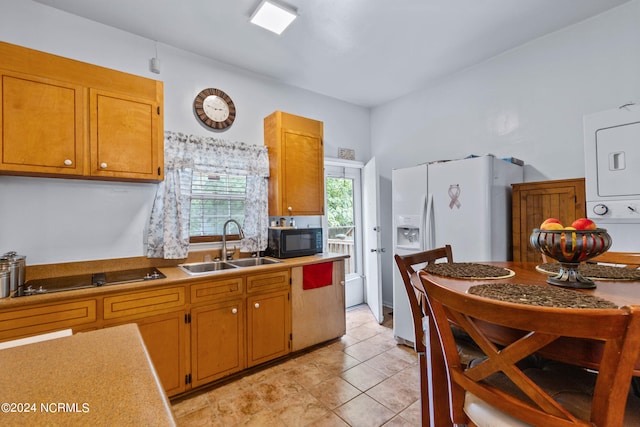 kitchen with black appliances, stacked washer and clothes dryer, sink, and light tile patterned flooring