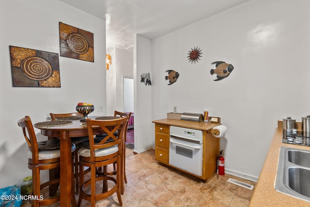 kitchen with light countertops, visible vents, a sink, and baseboards