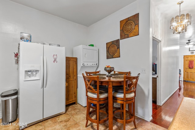 dining space featuring ceiling fan with notable chandelier, light hardwood / wood-style flooring, and stacked washer and dryer