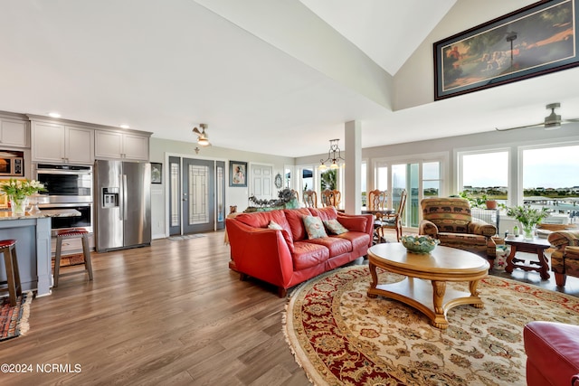 living room with hardwood / wood-style floors, high vaulted ceiling, and ceiling fan with notable chandelier