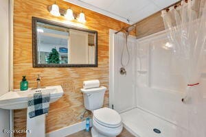 bathroom featuring a shower with shower curtain, toilet, and wooden walls