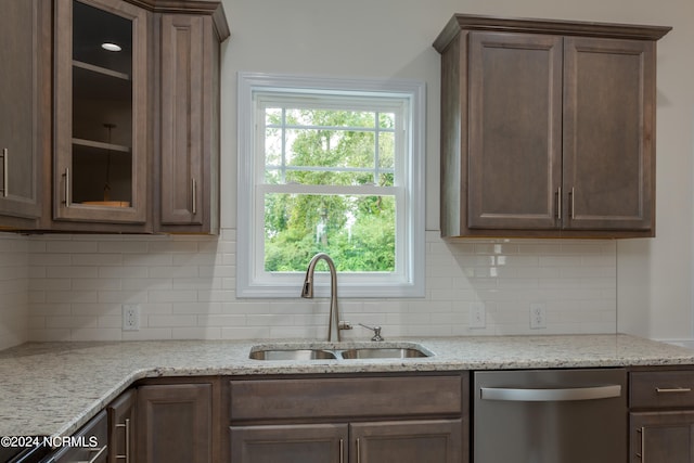 kitchen with light stone counters, sink, a healthy amount of sunlight, and stainless steel dishwasher