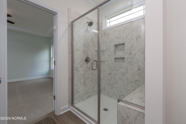 bathroom with crown molding, hardwood / wood-style floors, ceiling fan, and a shower with shower door