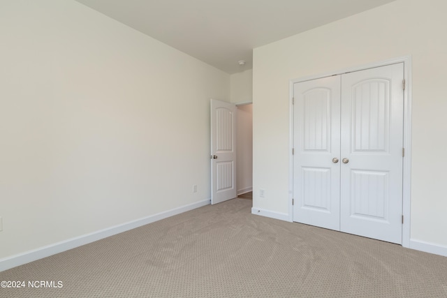 unfurnished bedroom featuring a closet and light colored carpet