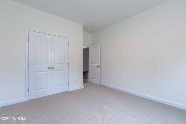 unfurnished bedroom with light carpet and a closet