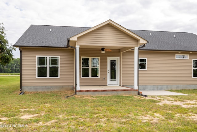 rear view of property with a lawn and ceiling fan