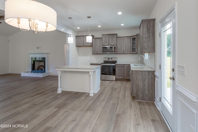 kitchen with sink, decorative light fixtures, light hardwood / wood-style flooring, stainless steel appliances, and a center island