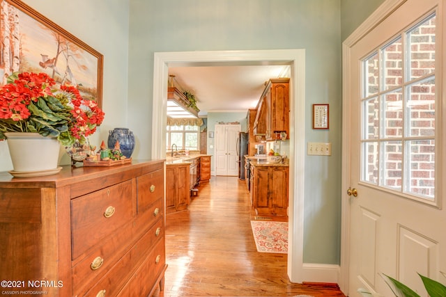 corridor with light hardwood / wood-style flooring and sink