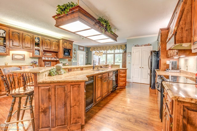 kitchen featuring light wood-type flooring, sink, a kitchen breakfast bar, appliances with stainless steel finishes, and ornamental molding