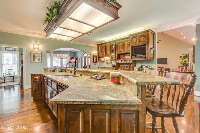 kitchen with a breakfast bar area, a textured ceiling, ornamental molding, dark hardwood / wood-style floors, and sink