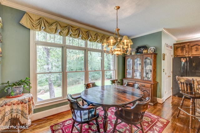 dining area featuring ornamental molding, an inviting chandelier, dark hardwood / wood-style flooring, and a healthy amount of sunlight