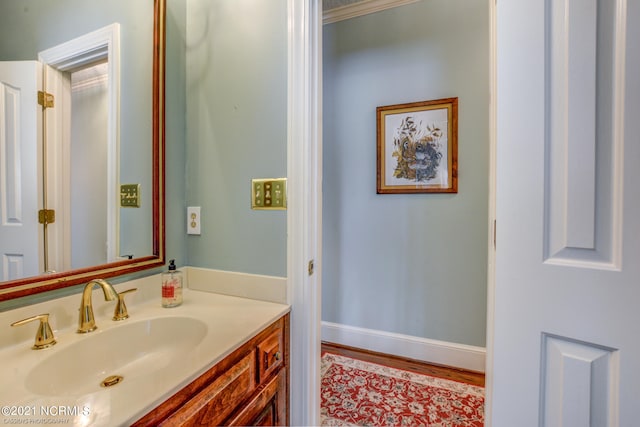 bathroom with ornamental molding, hardwood / wood-style floors, and vanity