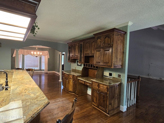 kitchen featuring a notable chandelier, light stone countertops, dark brown cabinetry, and dark hardwood / wood-style flooring