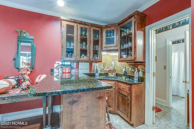 kitchen featuring dark stone countertops, a textured ceiling, crown molding, and kitchen peninsula