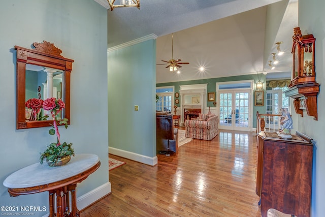 interior space with a textured ceiling, hardwood / wood-style flooring, crown molding, ceiling fan, and french doors