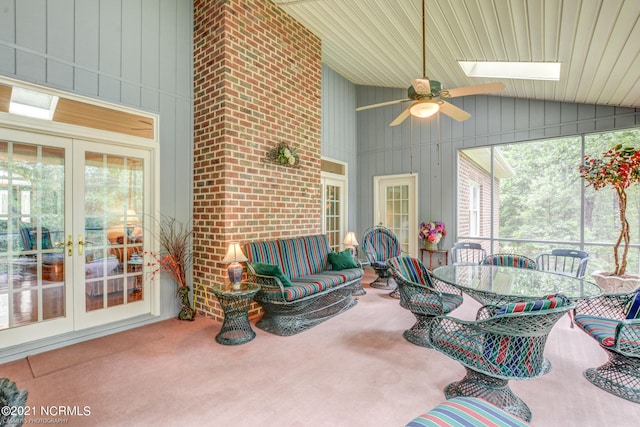 sunroom / solarium with vaulted ceiling with skylight, ceiling fan, and french doors