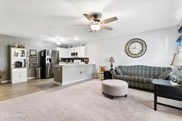 carpeted living area featuring ceiling fan, wood finished floors, and baseboards