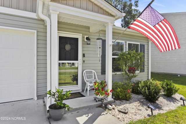 entrance to property with board and batten siding and an attached garage