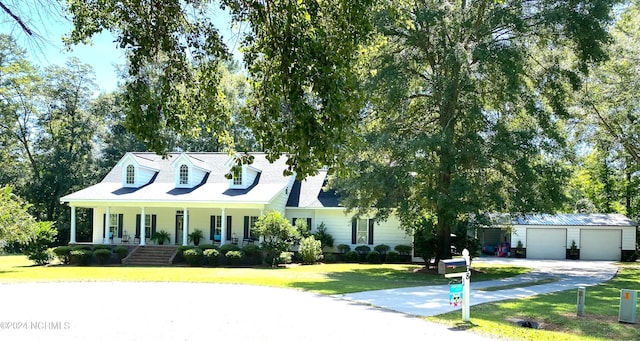 new england style home featuring a garage, a front yard, and a porch