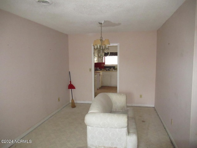 unfurnished room with a textured ceiling and a chandelier