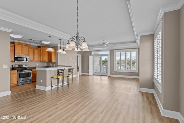 kitchen with ceiling fan with notable chandelier, stainless steel appliances, light hardwood / wood-style floors, a kitchen breakfast bar, and pendant lighting