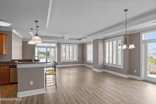 kitchen with a kitchen breakfast bar, ceiling fan with notable chandelier, wood-type flooring, crown molding, and stainless steel dishwasher