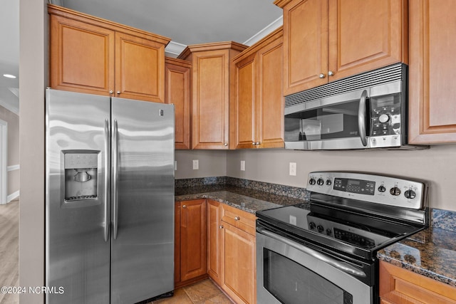 kitchen with dark stone countertops, appliances with stainless steel finishes, and ornamental molding